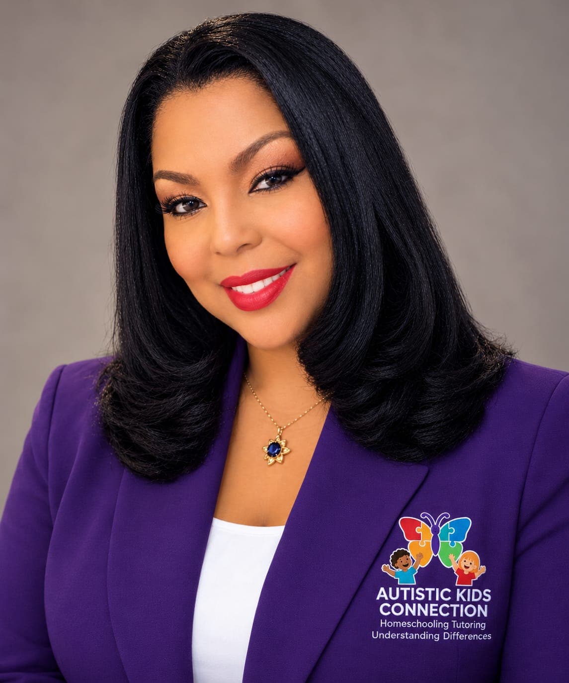Stacey Moraine, smiling, wearing a purple blazer with the Autistic Kids Connection logo